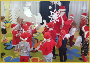 Dzieci wręczają listy Mikołajowi.